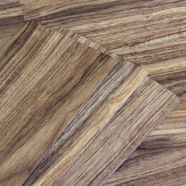 Close-up of wood-look flooring planks layered diagonally, showing natural grain patterns in warm brown and tan tones.